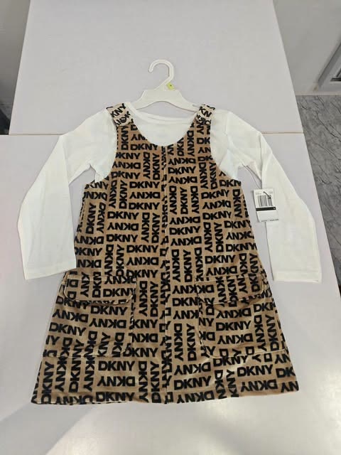 Printed pinafore dress and white top displayed on a hanger